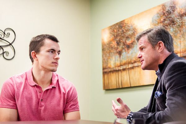 Empathetic one-on-one professional counseling session between a licensed clinician and patient in a comfortable room.